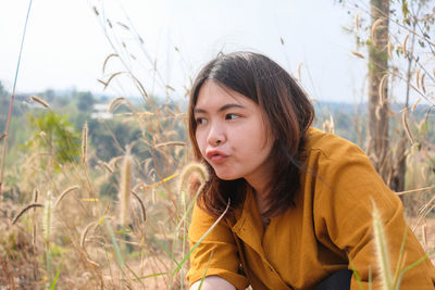 Portrait of young woman looking away on field