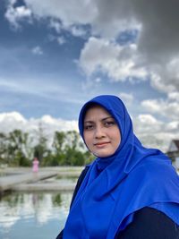 Portrait of woman standing against blue sky