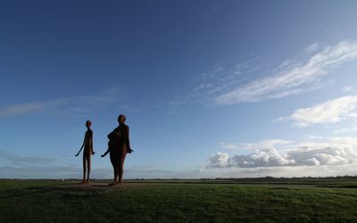 Woman of steel standing on field against sky