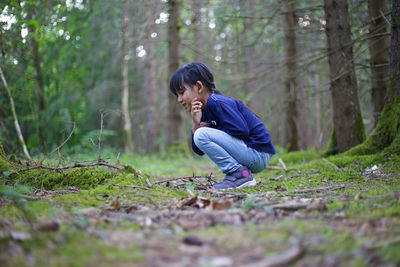 Side view of young girl looking at forest floor