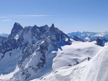 Scenic view of snow covered mountains against blue sky