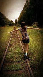 Rear view of woman walking on railroad track