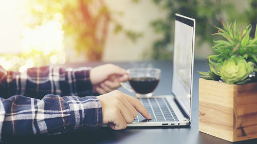 Midsection of man using mobile phone while sitting on table