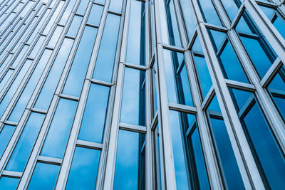 Low angle view of glass building against blue sky