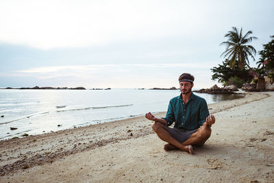 Man meditating while sitting at beach