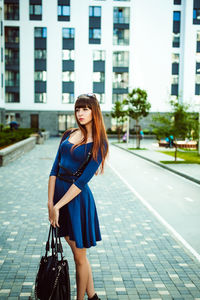 Full length portrait of young woman standing in city