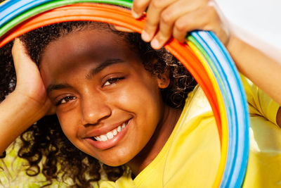 Close-up portrait of smiling girl looking through plastic hoops