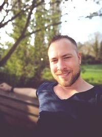 Portrait of smiling young man against trees