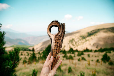 Close-up of hand holding rock against sky