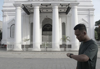 Side view of young man against building