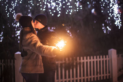 Rear view of man and woman standing at night