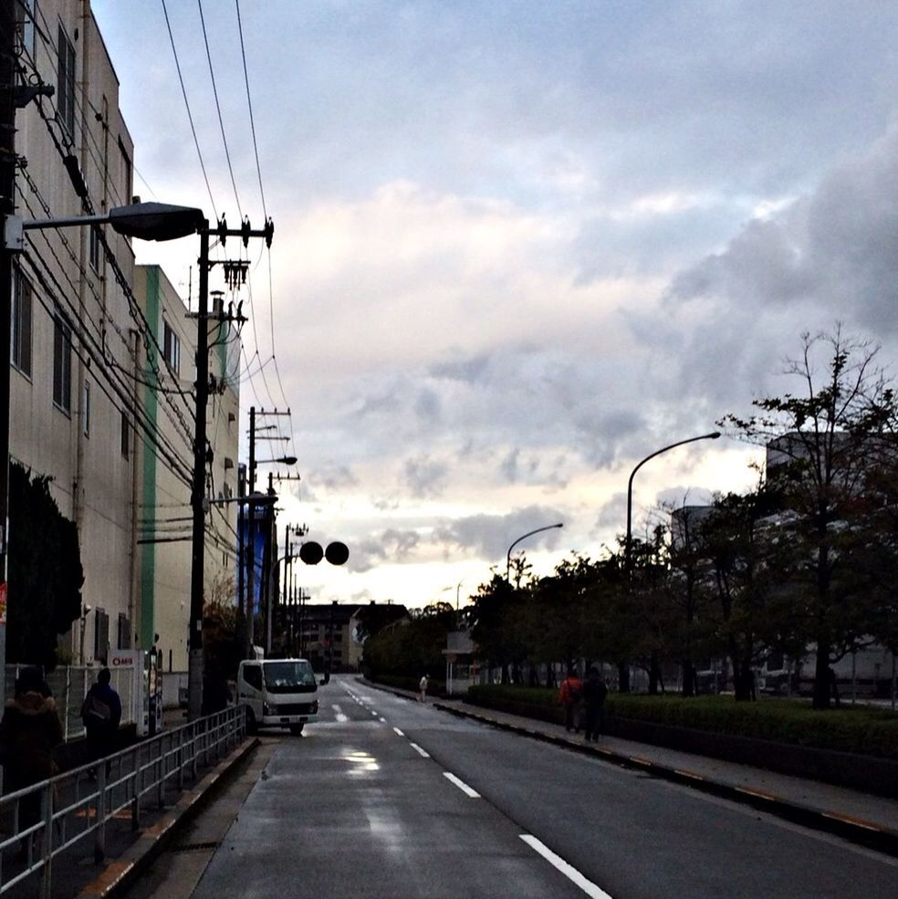 transportation, sky, electricity pylon, power line, building exterior, the way forward, cloud - sky, built structure, road, street, car, architecture, city, mode of transport, diminishing perspective, railroad track, cloud, cloudy, land vehicle, vanishing point