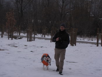 Portrait of woman with dog walking on snow field