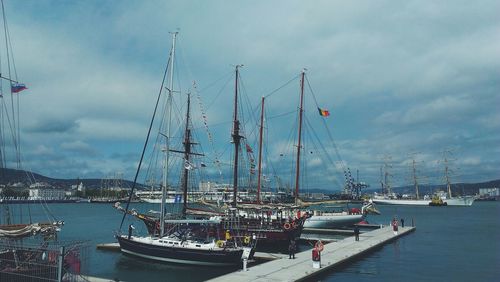 Boats in harbor against cloudy sky