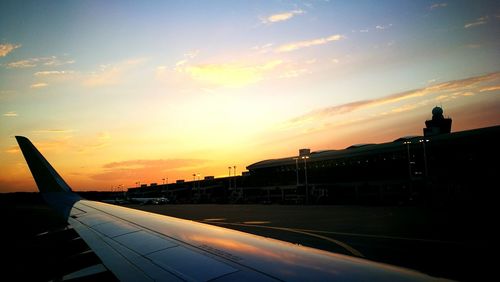 Airplane on airport runway against sky during sunset