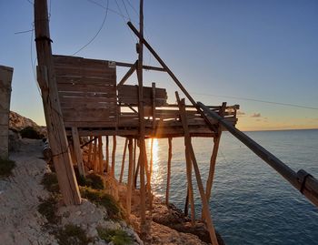 Built structure by sea against clear sky during sunset