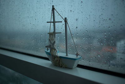 Raindrops on glass window during rainy season with a boat model.