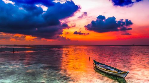 Scenic view of sea against cloudy sky during sunset