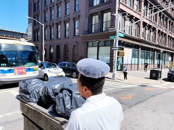 Rear view of man and vehicles on street in city