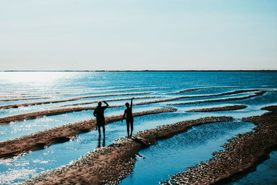 People standing at beach against clear sky