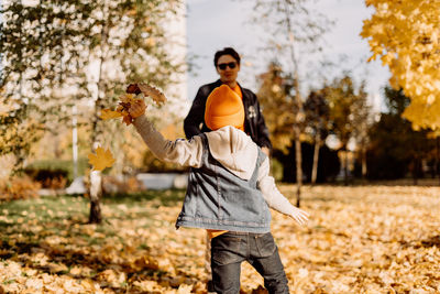 Side view of young woman standing against trees