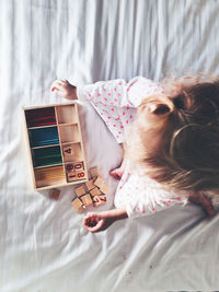 Directly above shot of girl playing with toy blocks and crayons on bed