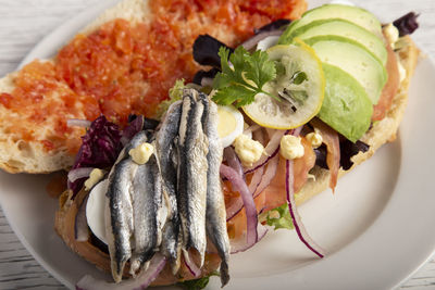 Close up of a salmon sandwich, anchovies, boiled egg, avocado. creative spanish cuisine