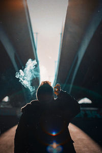 Rear view of man smoking while standing outdoors