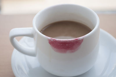 Close-up of red lipstick on coffee cup