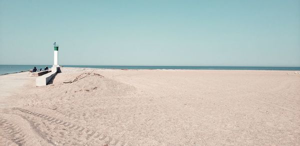 Lighthouse on beach against clear sky