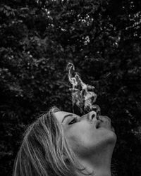 Close-up portrait of woman against trees