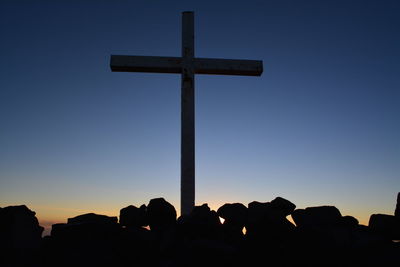 Silhouette cross against clear blue sky