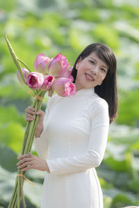 Portrait of a smiling young woman holding pink flower