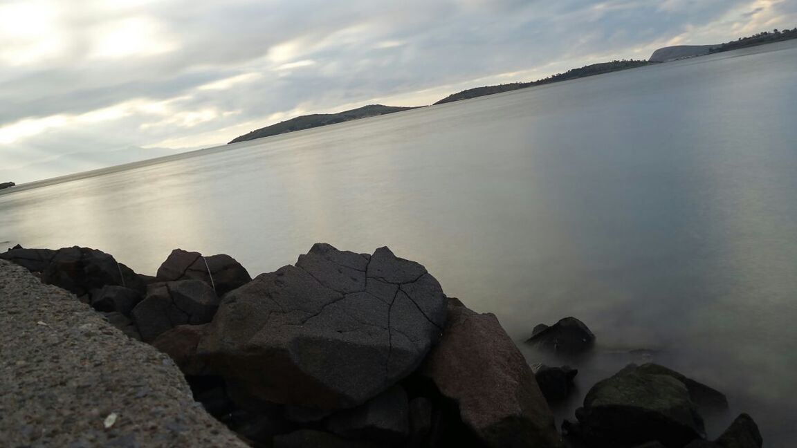 water, sky, tranquility, tranquil scene, beauty in nature, scenics, cloud - sky, rock - object, nature, reflection, lake, cloudy, idyllic, sea, weather, cloud, outdoors, sunset, rock formation, dusk