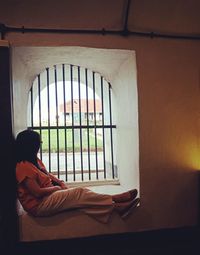 Side view of woman sitting on bed