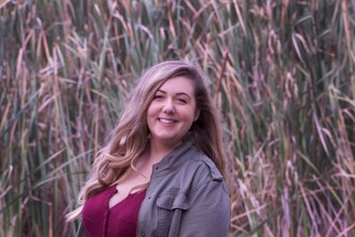 Portrait of smiling woman standing against plants