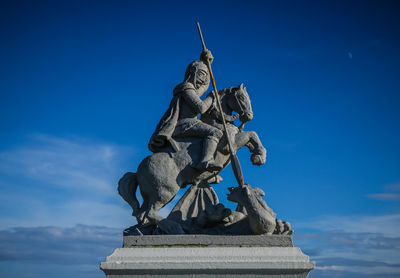 Low angle view of statue against blue sky