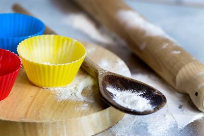 Close-up of cupcake molds by flour in wooden spoon