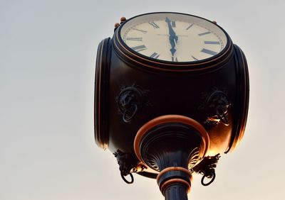 Low angle view of clock against sky