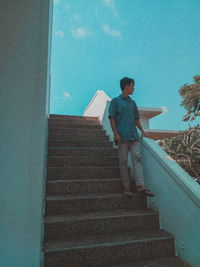 Rear view of man standing on staircase against sky