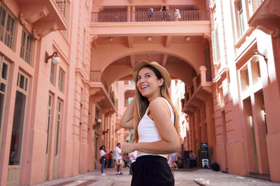 Portrait of young woman standing against building