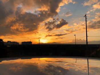 Silhouette bridge against dramatic sky during sunset