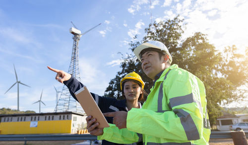 Engineers examining windmill through digital tablet