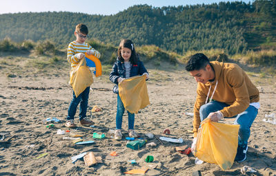 Siblings picking garbage at beach