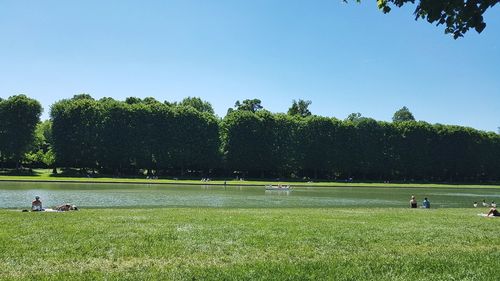 People playing soccer field against sky