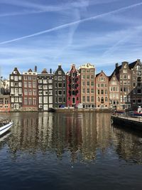 Buildings by canal against sky in city