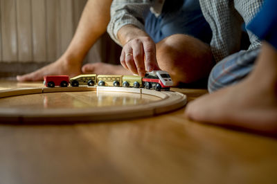 Father playing with toy train on floor at home