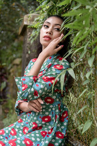 Portrait of young woman standing amidst plants