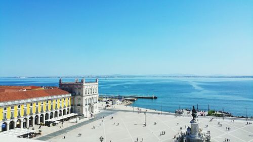 Tourists on shore against clear blue sky