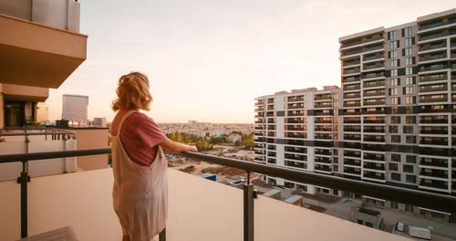 Side view of young woman standing against building